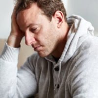 Man in gray sweatshirt appears stressed