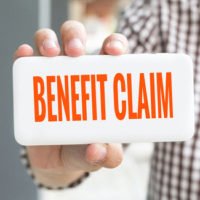 man holding up a card that says benefit claim